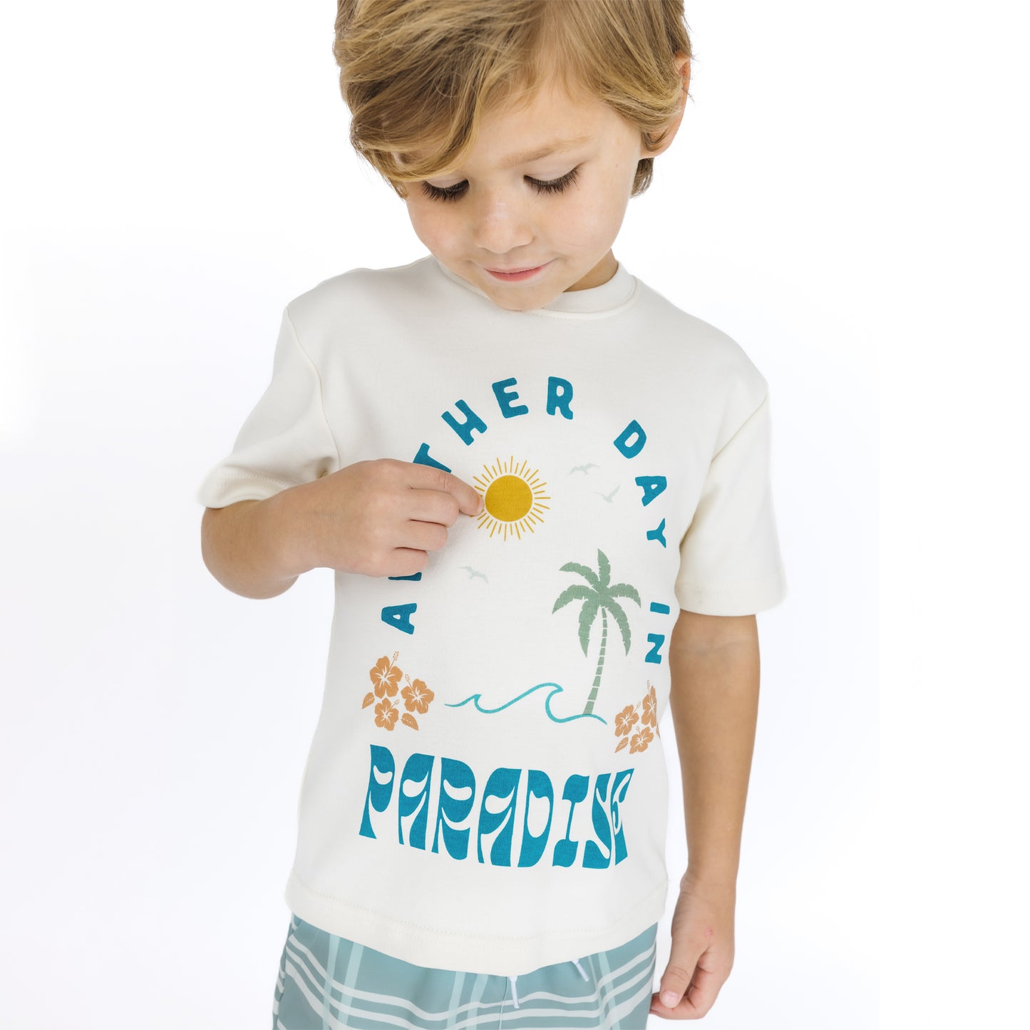 Child wearing a white t-shirt with tropical graphics and text on a white background