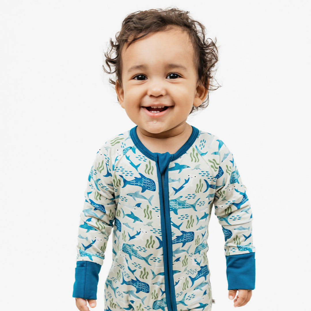 Baby smiling while standing in our Shark Friends Bamboo Convertible Pajama.