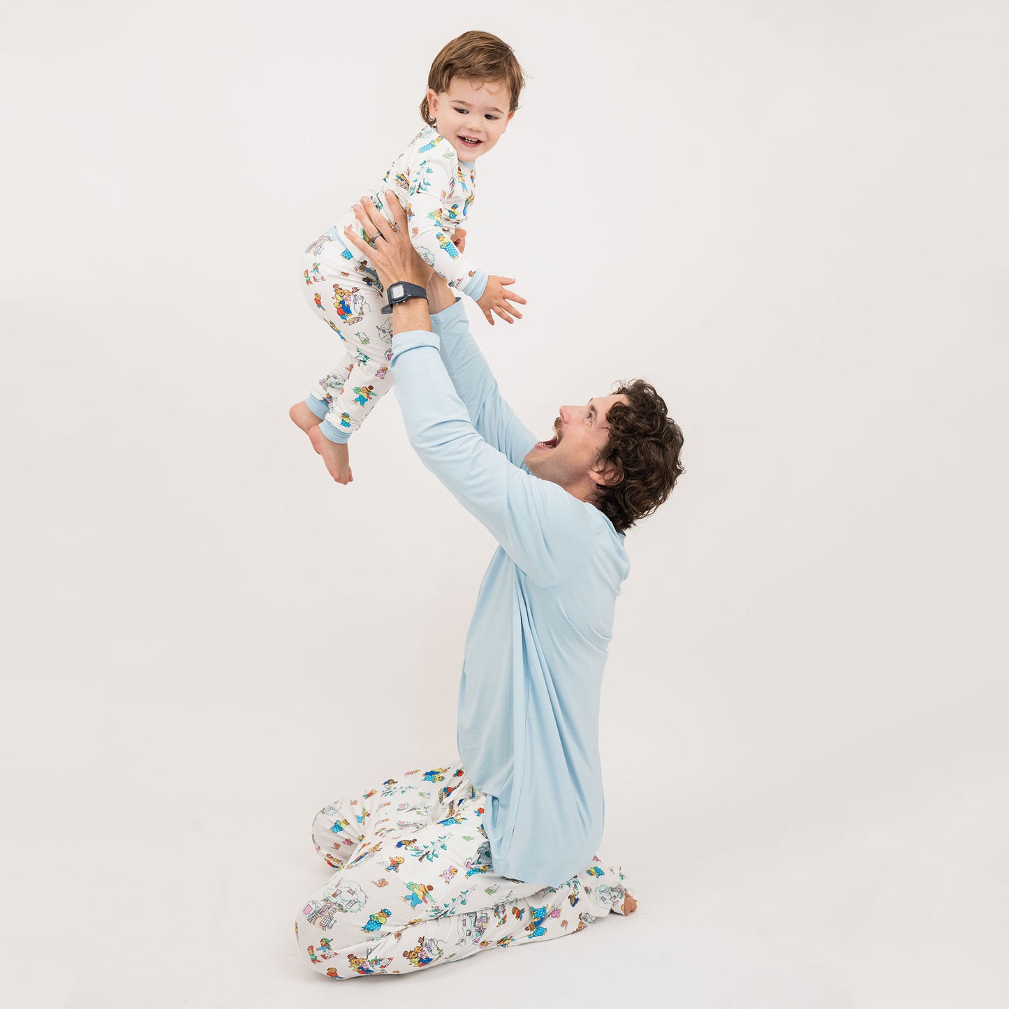 Man and child wearing matching pajamas against a plain background