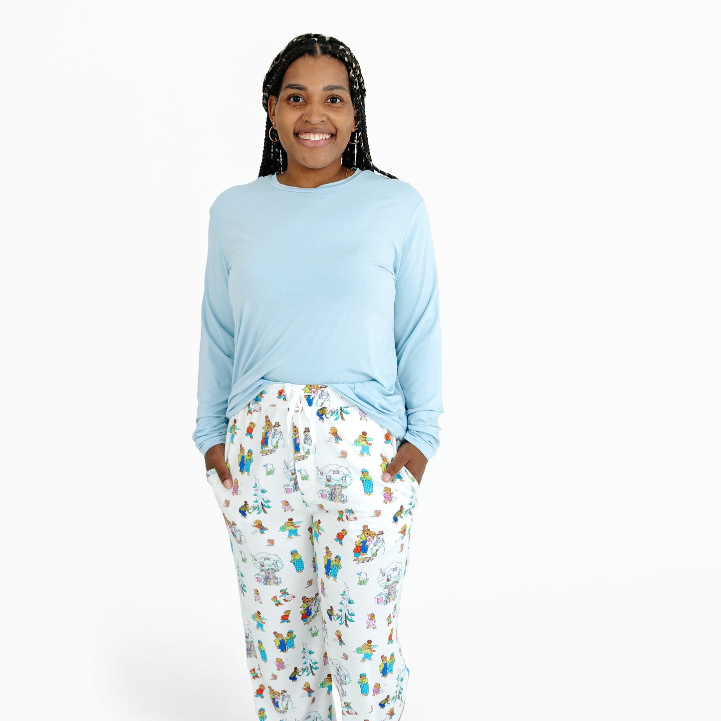 Woman wearing a light blue long-sleeve top and patterned pajama pants on a white background