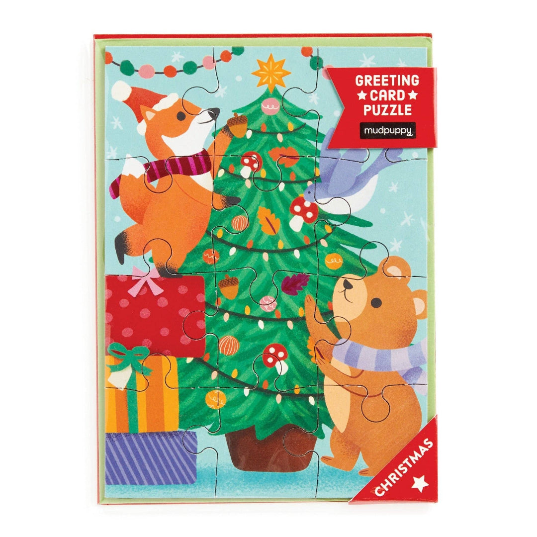 Greeting card puzzle with a fox and bear decorating a Christmas tree, featuring Mudpuppy branding.