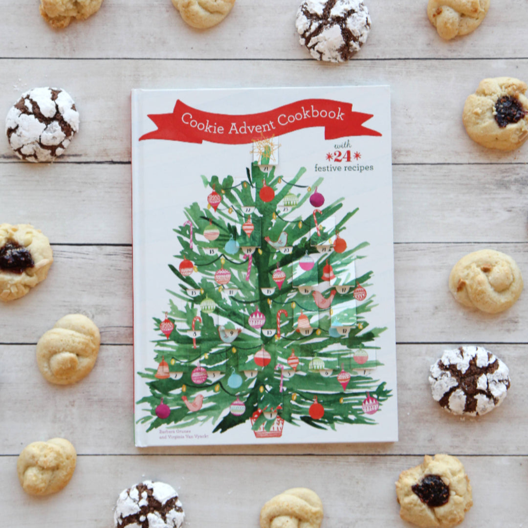 Cookie Advent Cookbook with Christmas tree design surrounded by cookies on a wooden surface