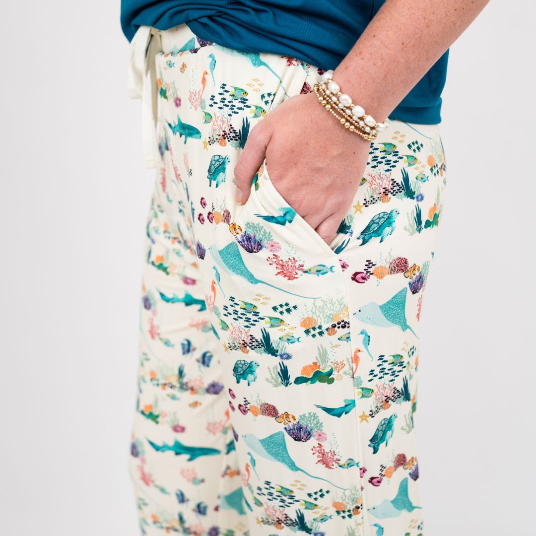 Woman wearing our Emerson and Friends Coral Reef Bamboo Relaxed Lounge Pajama Pants, featuring a serene ocean-inspired print with sea turtles, sharks, coral, and tropical fish on ultra-soft bamboo fabric perfect for all-day comfort and night.