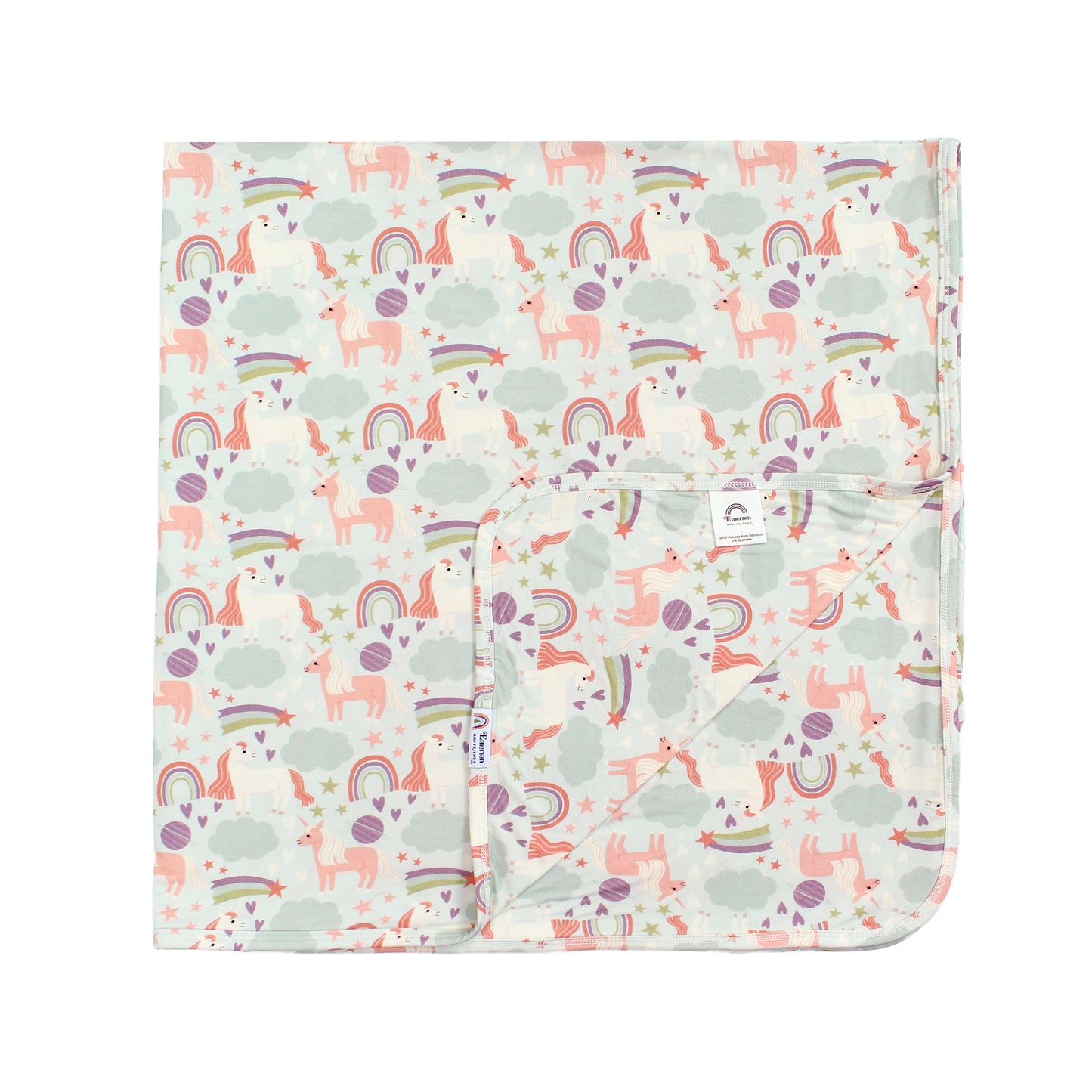 Flat lay picturing our Magical Unicorn Luxury Bamboo blanket on a white background. The print includes unicorns, rainbows, clouds, planets, stars, and hearts. The colors are purple, pink, and blu, with hints of green.