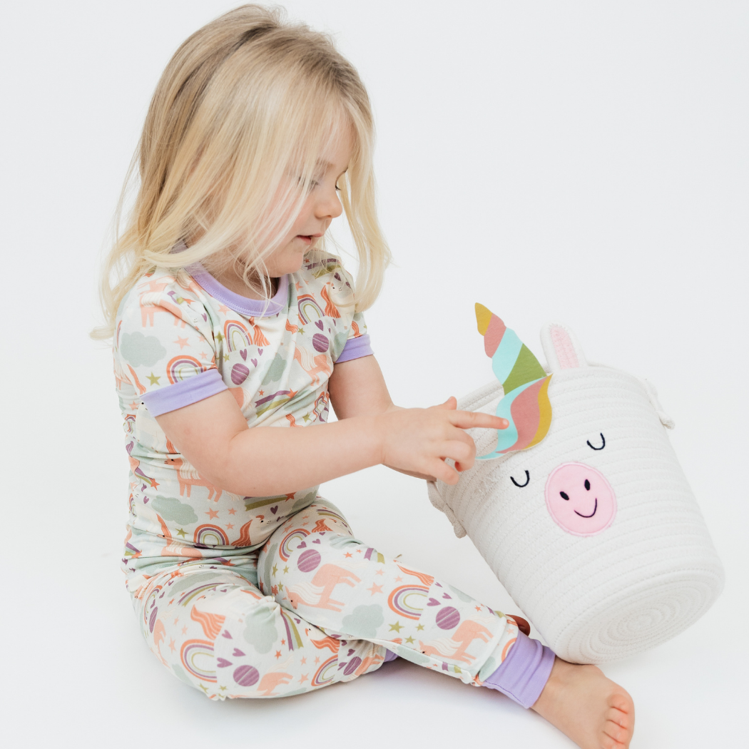 Little girl wearing our Magical Unicorn Bamboo Pajama set holding the Magical Unicorn Rope Basket.