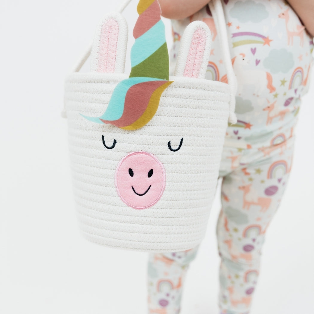 Little girl wearing our Magical Unicorn Bamboo Pajama set holding the Magical Unicorn Rope Basket.
