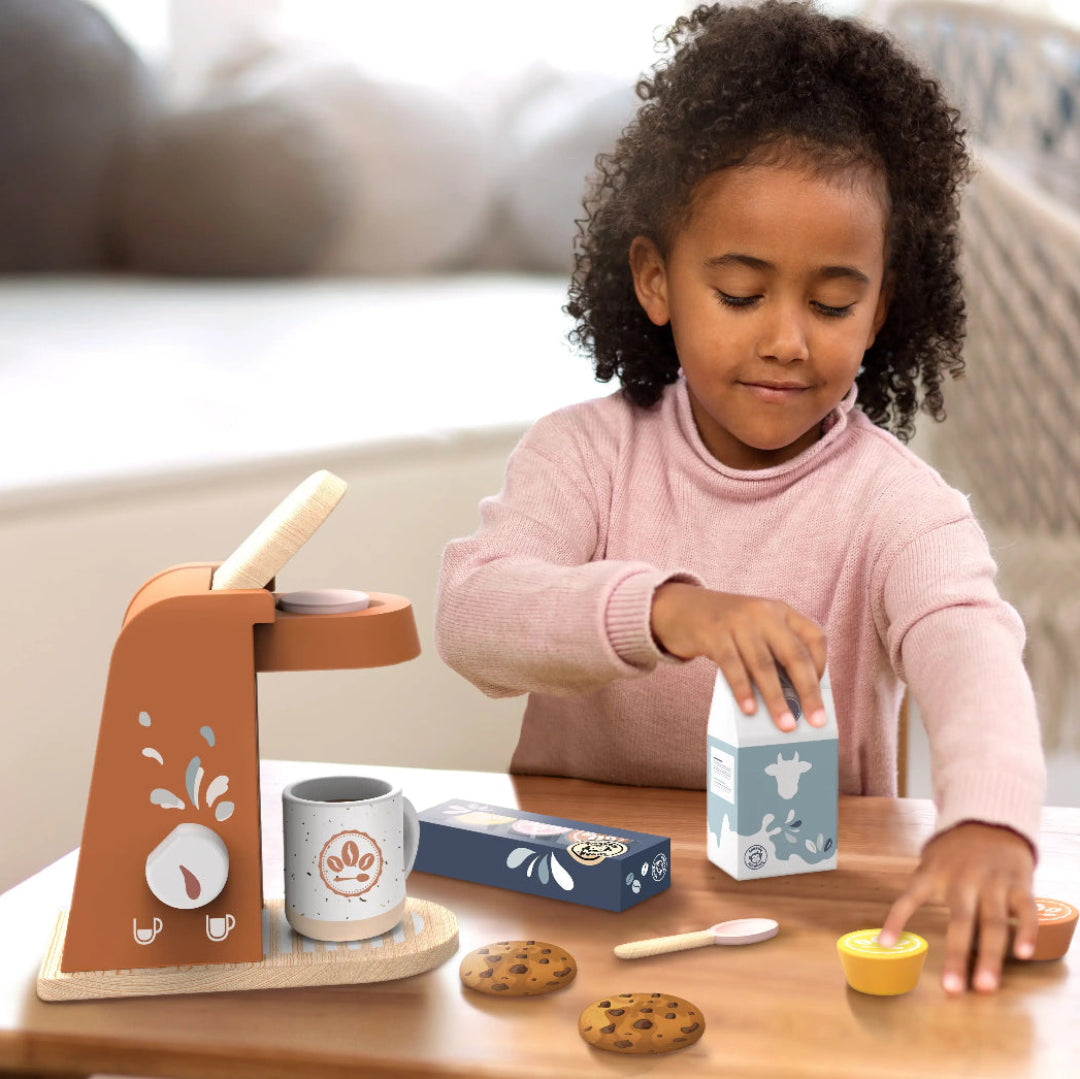 a little girl playing with a pretend wooden coffee maker