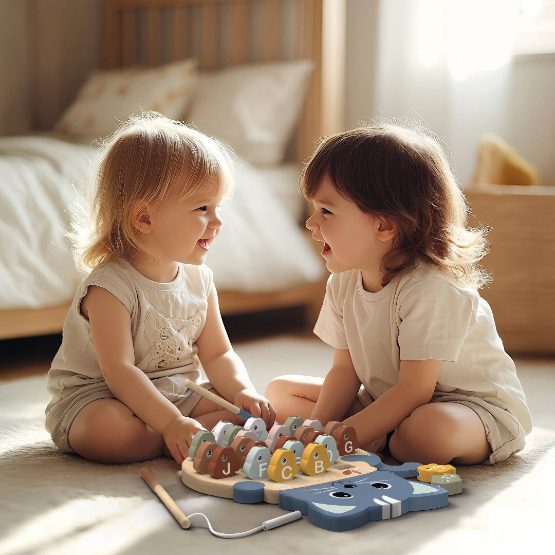 2 toddler asked kids playing a fishing game together sitting on a bedroom floor with a bed in the background