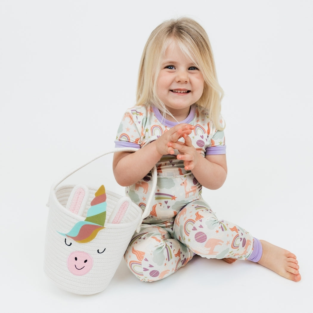 Little girl wearing our Magical Unicorn Bamboo Pajama set holding the Magical Unicorn Rope Basket.