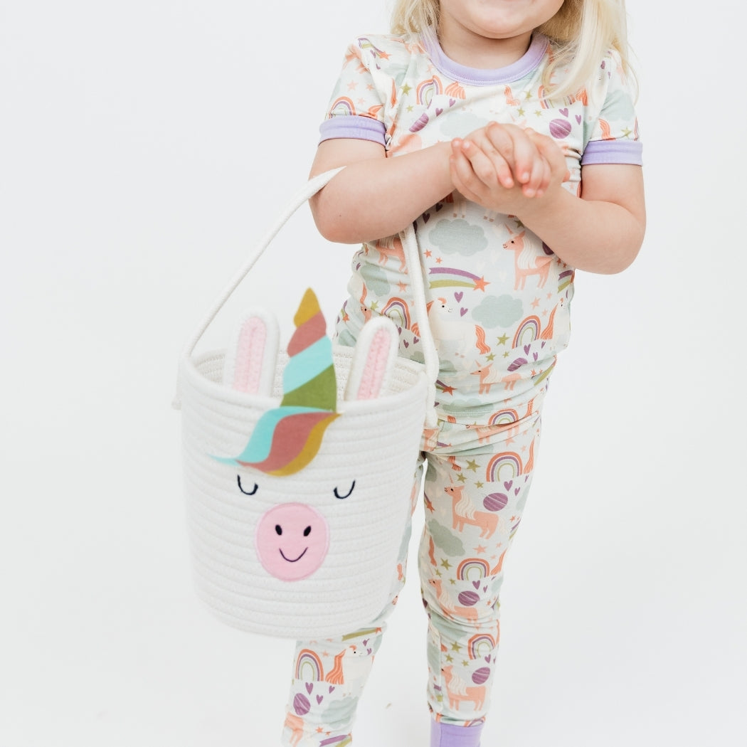 Little girl wearing our Magical Unicorn Bamboo Pajama set holding the Magical Unicorn Rope Basket.