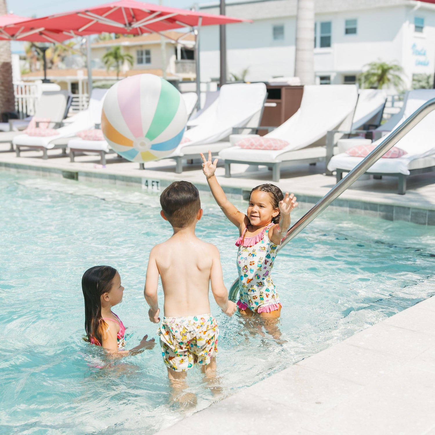 Siblings playing in the pool with our Arthur's Family Vacation one piece and swim trunks with a playful print of Arthur™ in swimwear surrounded by fun beach props — perfect for family getaways.