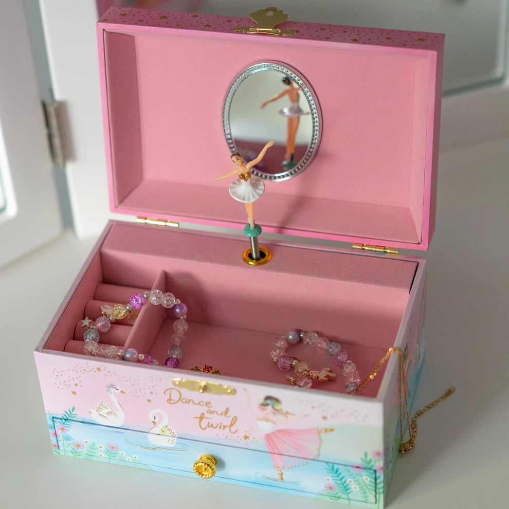 a jewelry box thats pink inside and has a spinning ballerina and on the outside it has a ballerina dancing across a pond with swans