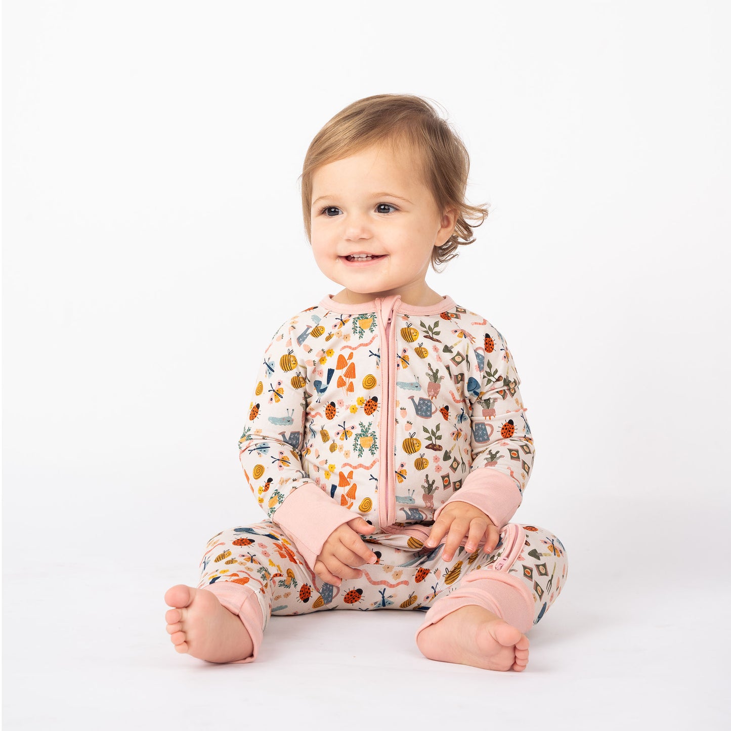 Baby wearing our convertible Garden Friends Pajama with pink trim.