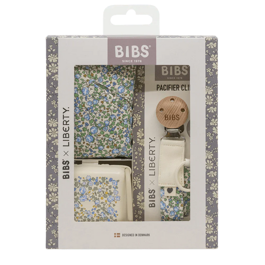 a baby gift set made by the brand BIBS and it includes a floral patterned baby bib, a pacifier clip, and a floral pacifier storage case