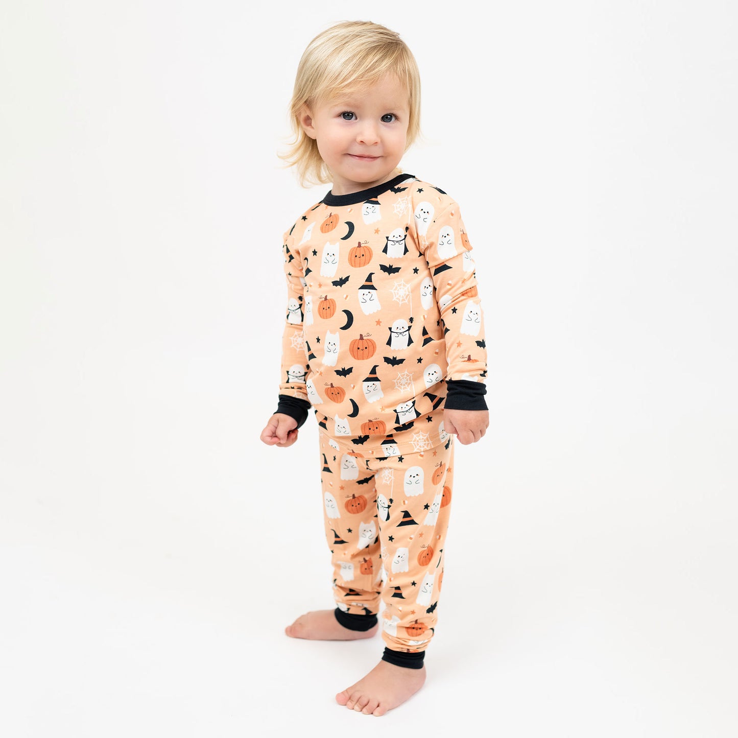 Child wearing Boo-Tastic Halloween bamboo two-piece pajamas with glow-in-the-dark ghost and pumpkin print.