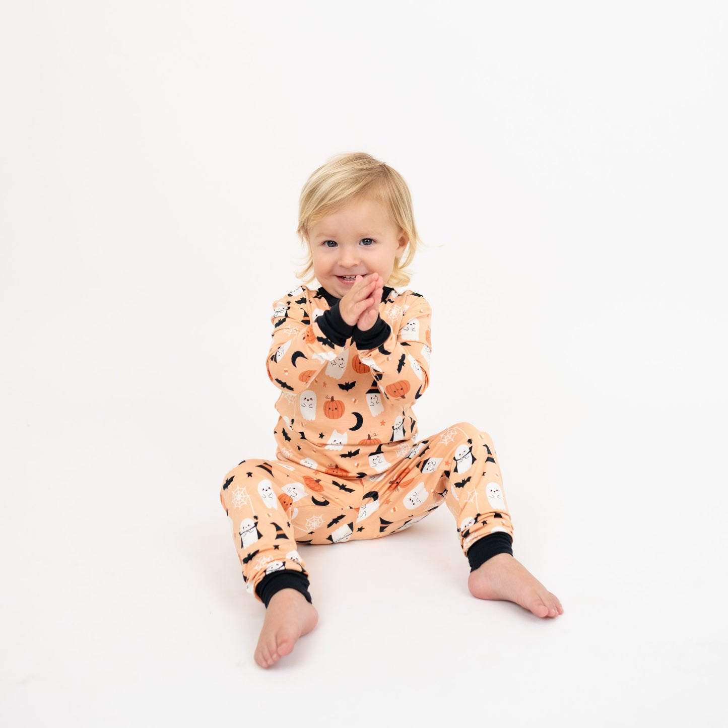Child smiling while wearing Boo-Tastic Halloween bamboo two-piece pajamas with ghost and pumpkin print.