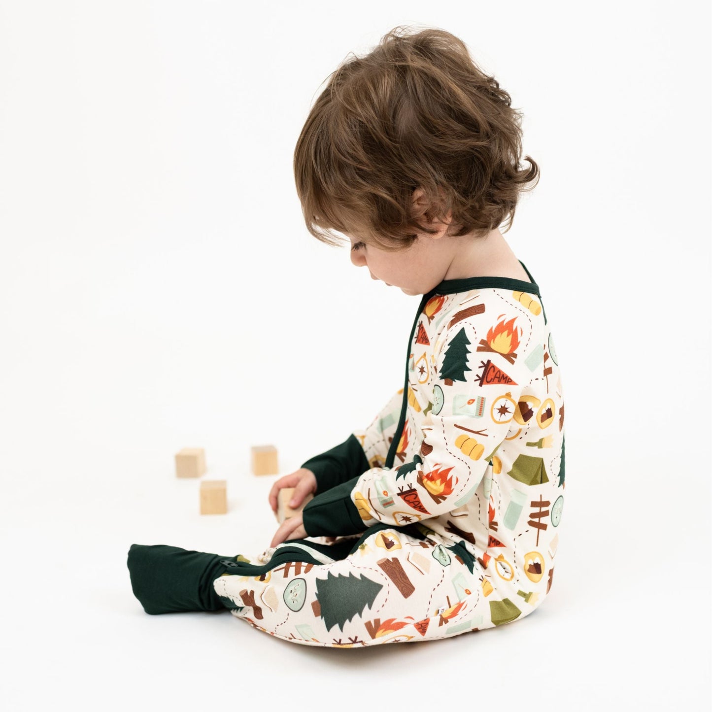 Baby boy wearing our Camp Emerson convertible. Featuring cozy camping-themed print featuring tents, campfires, s’mores, compasses, and nature icons—perfect for family pajamas or outdoor-inspired baby essentials.