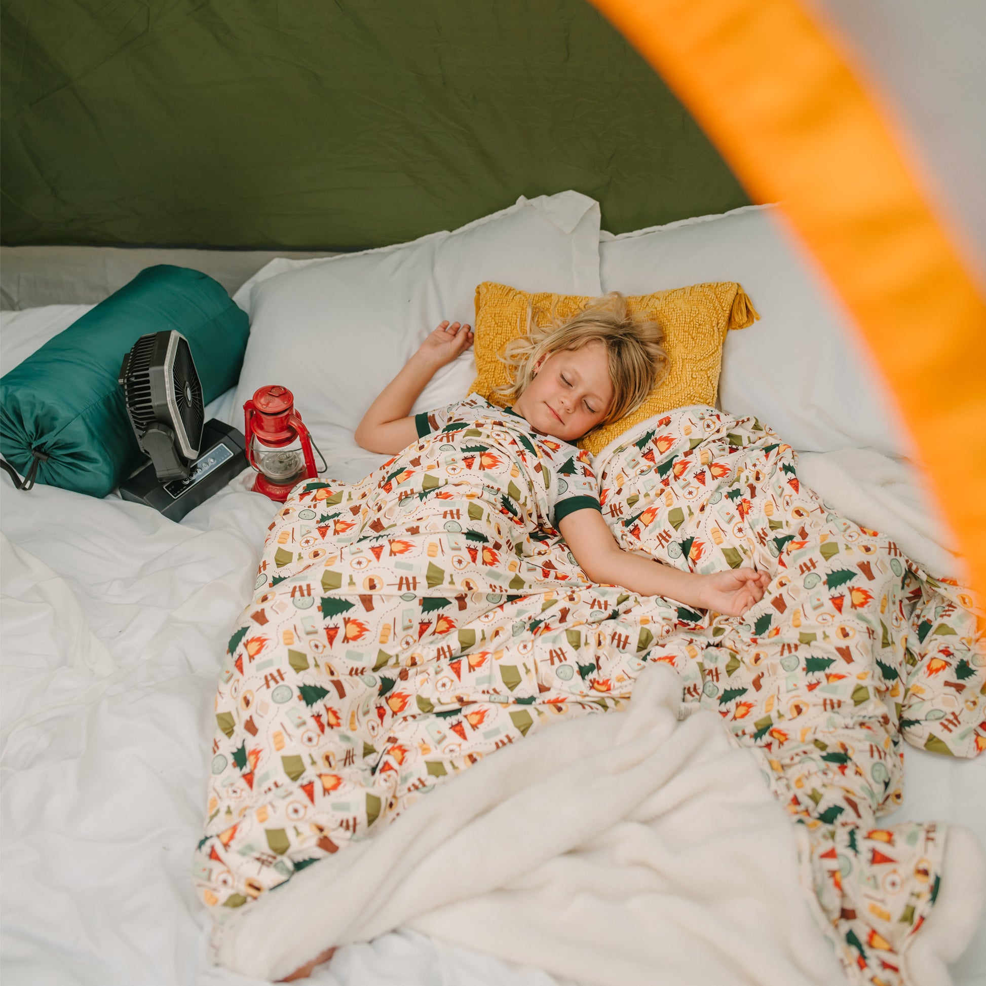 Child sleeping inside a tent wrapped in Camp Emerson bamboo and fleece camping blanket.