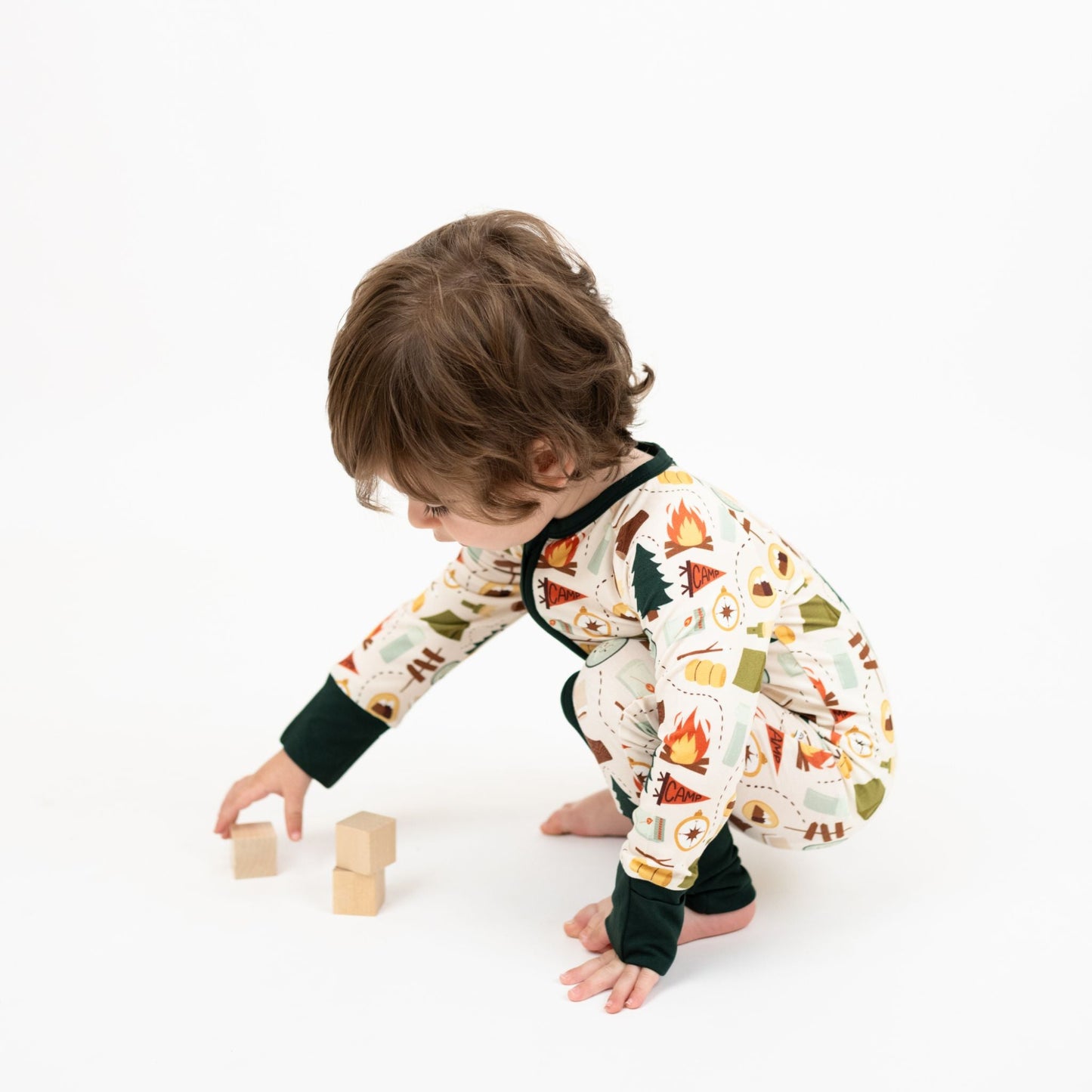 Baby boy wearing our Camp Emerson convertible. Featuring cozy camping-themed print featuring tents, campfires, s’mores, compasses, and nature icons—perfect for family pajamas or outdoor-inspired baby essentials.