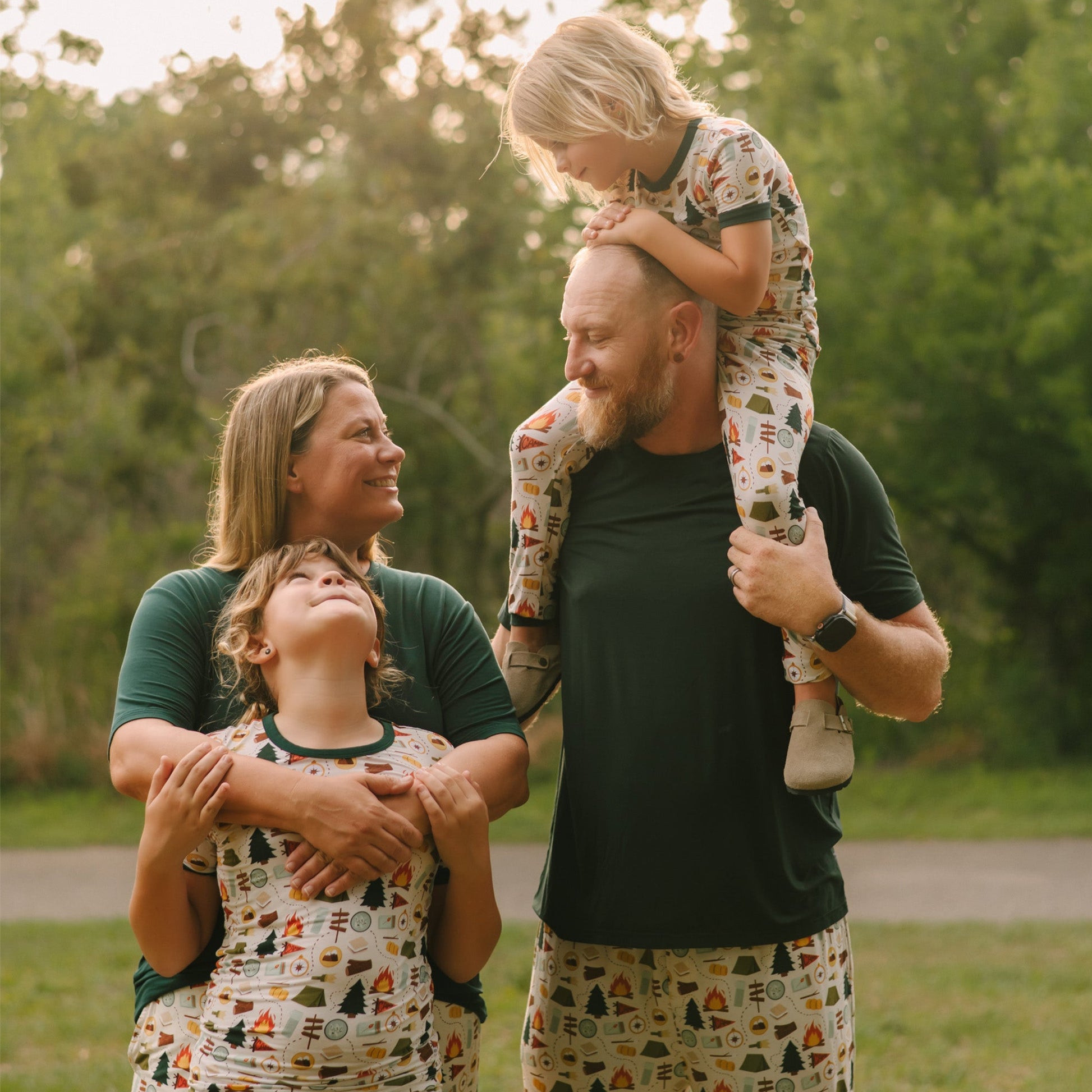 Family photo with kids in Camp Emerson print bamboo pajamas and parents in matching solid tops, outdoors with dog.