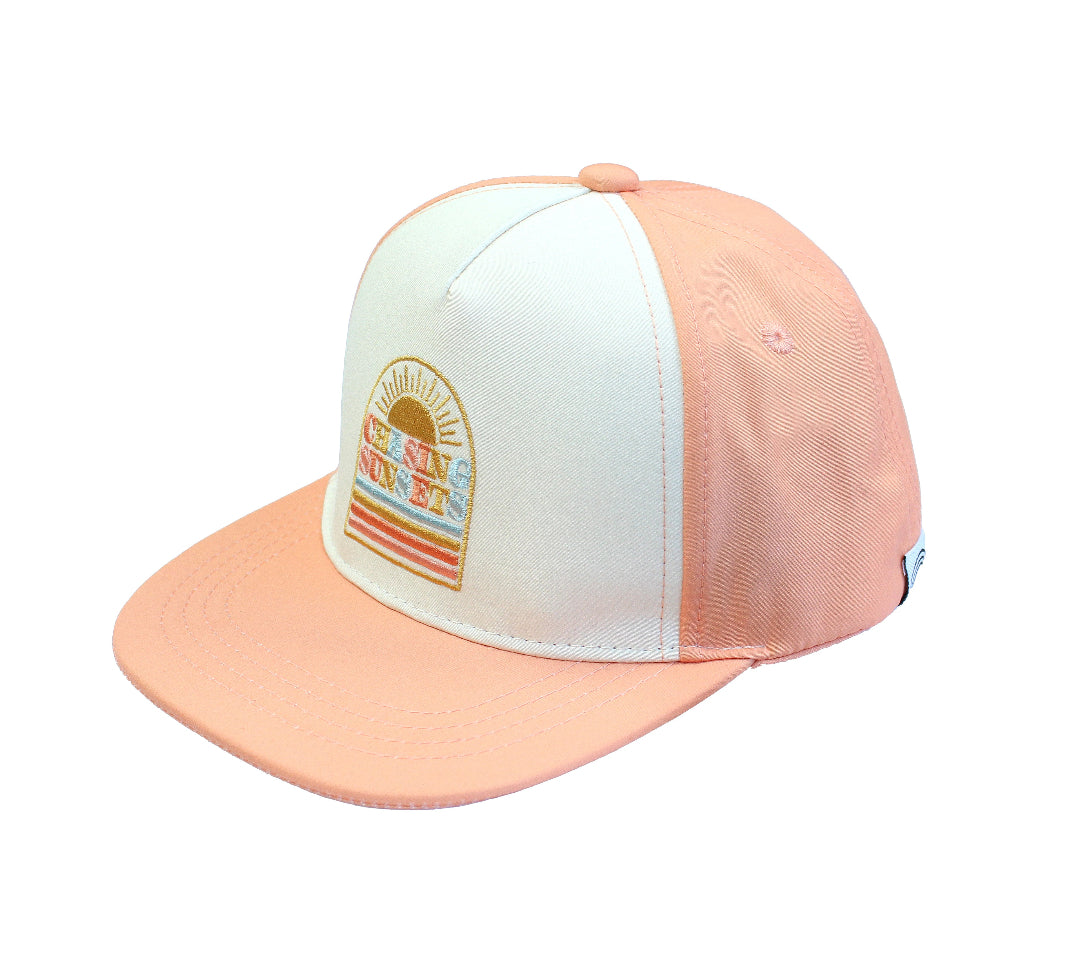 Flat Lay image of our Chasing Sunsets Snapback hat for babies and kids. The hat has a peach rim and back while the "Chasing Sunsets" emblem is placed on the white canvas in the front.