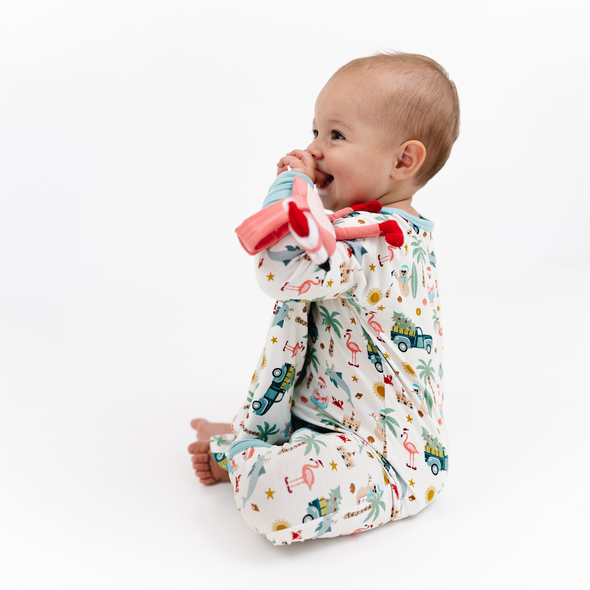 Baby wearing a colorful outfit with cartoon designs, sitting on a white background