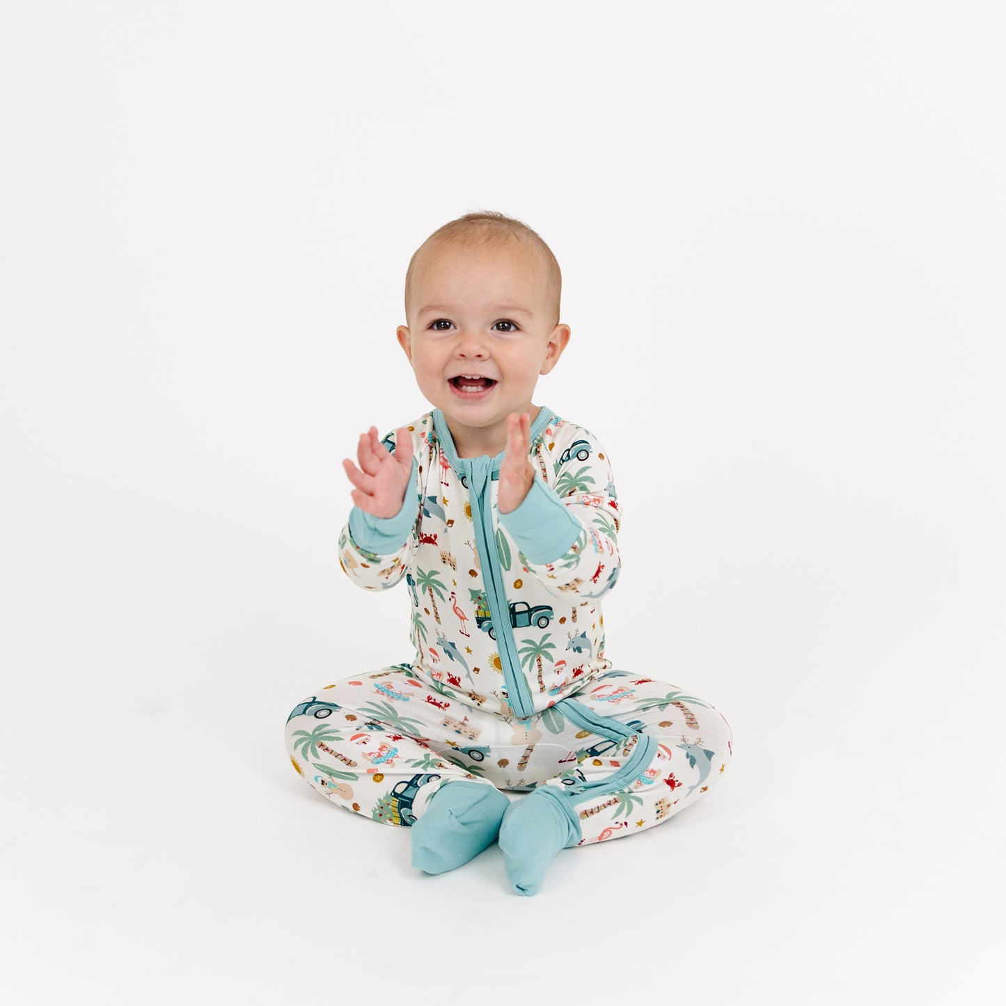 Baby wearing a patterned onesie with blue accents on a white background