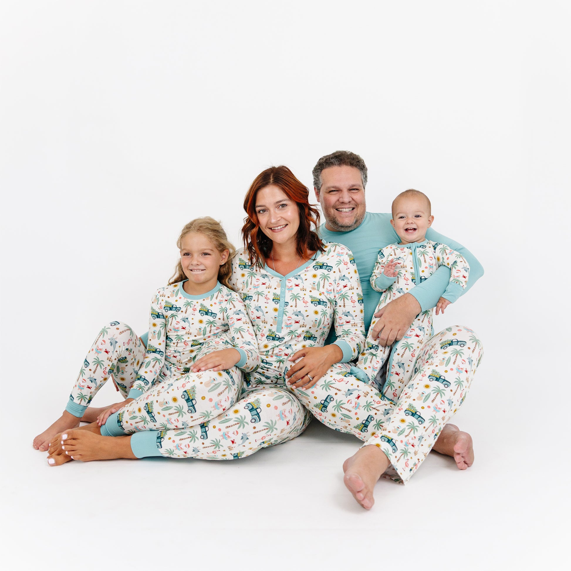Family of four wearing matching pajamas on a white background