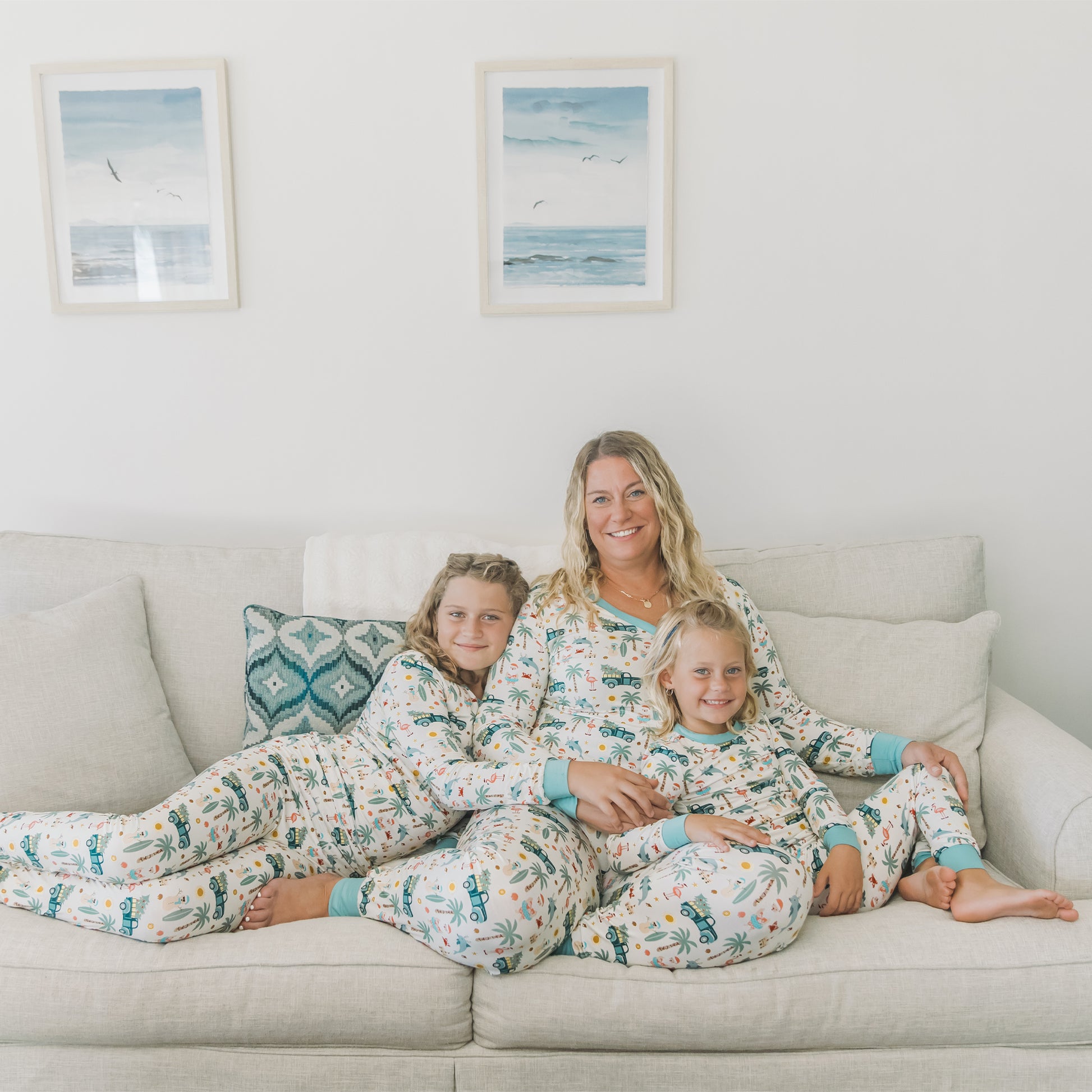 Woman and two children sitting on a couch wearing matching pajamas in a cozy living room.