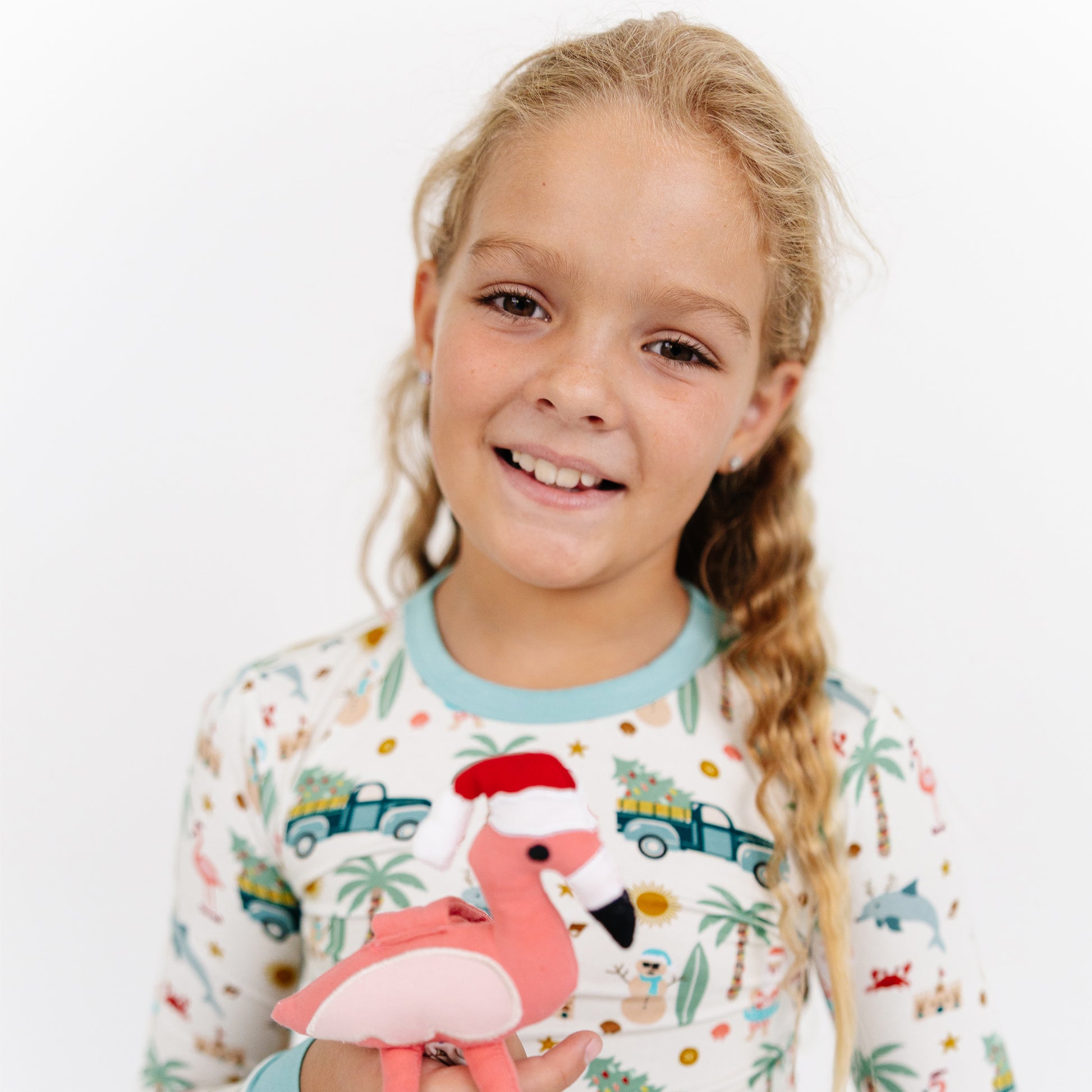 Young girl wearing pajamas with a flamingo design, holding a pink flamingo toy.