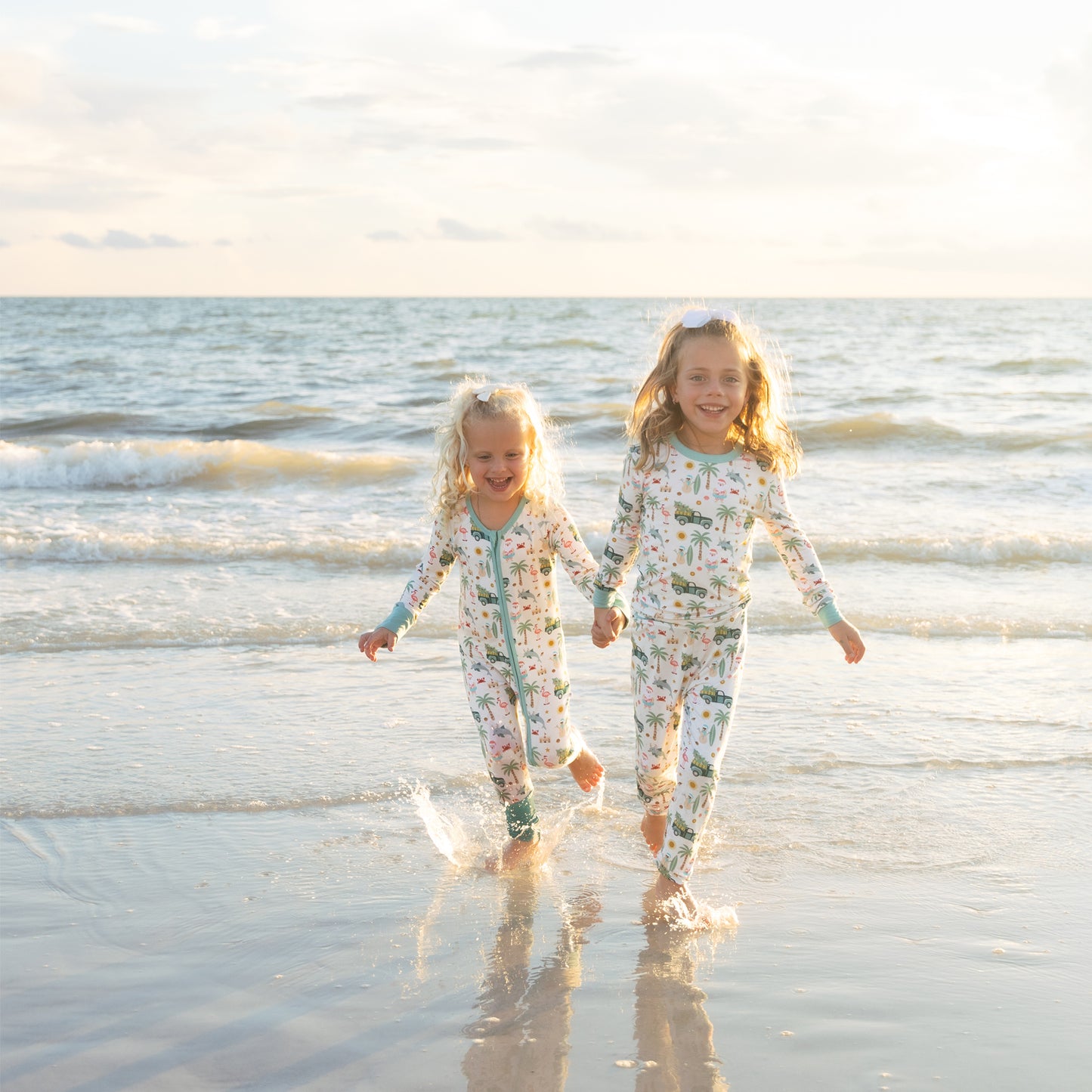 Two children in matching outfits running on a beach with waves in the background