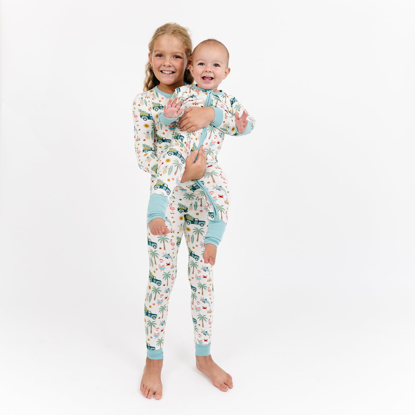 Two children wearing matching pajamas with a vehicle pattern on a white background
