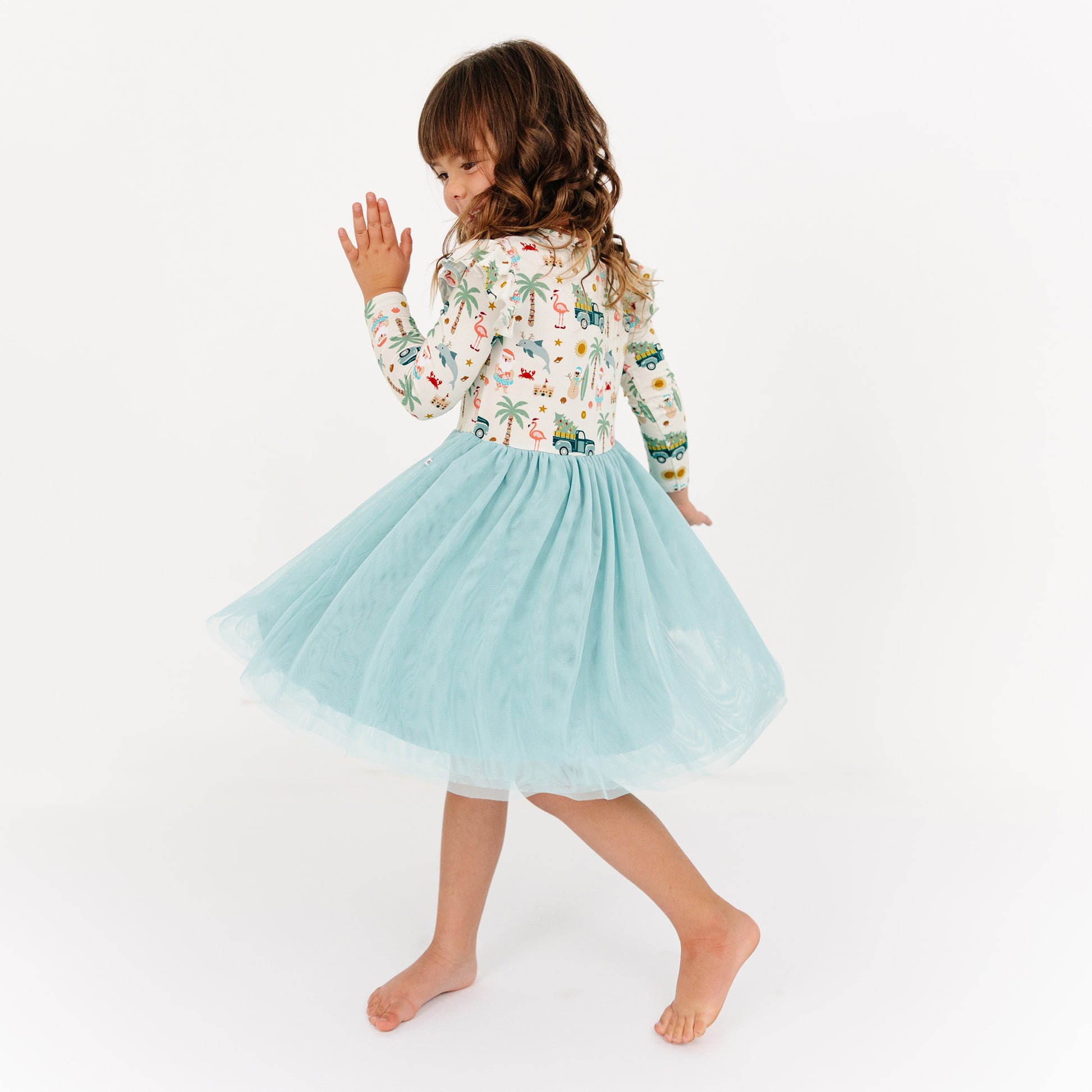 Young girl wearing a floral top and light blue tulle skirt on a white background