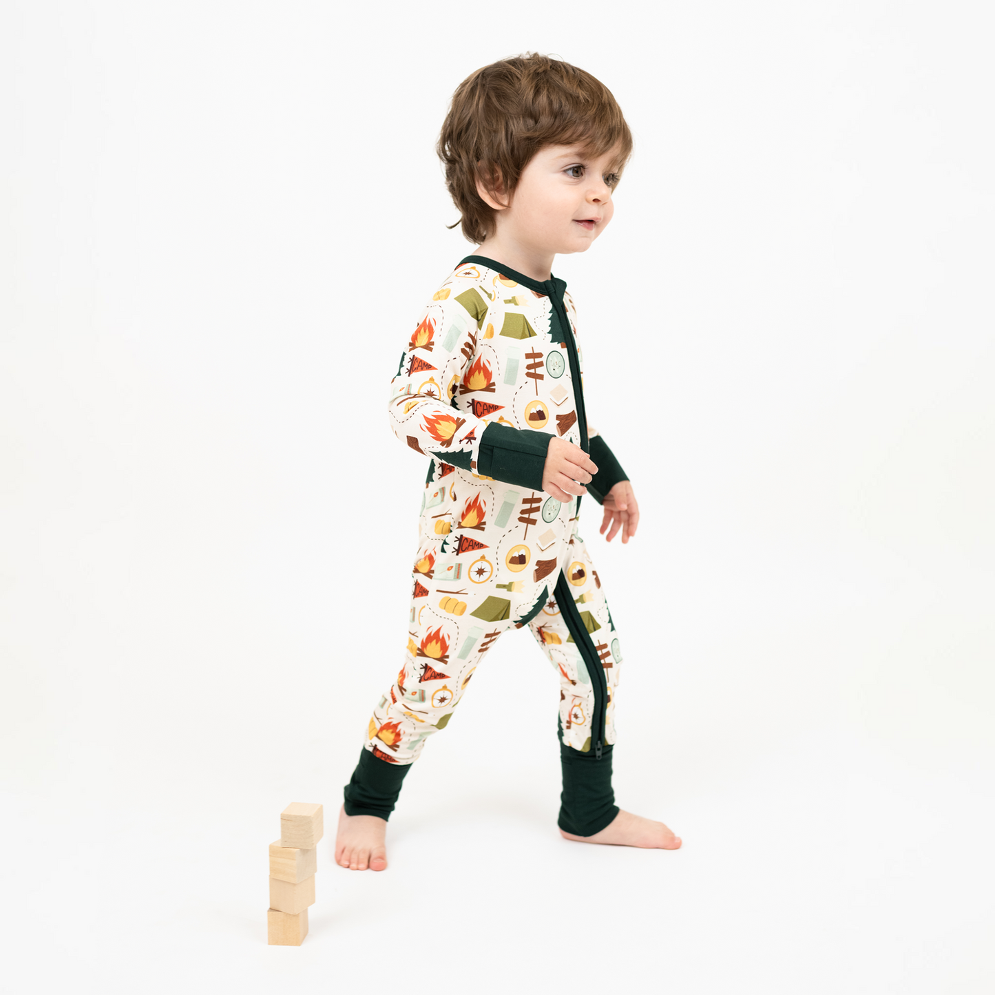 Baby boy wearing our Camp Emerson convertible. Featuring cozy camping-themed print featuring tents, campfires, s’mores, compasses, and nature icons—perfect for family pajamas or outdoor-inspired baby essentials.