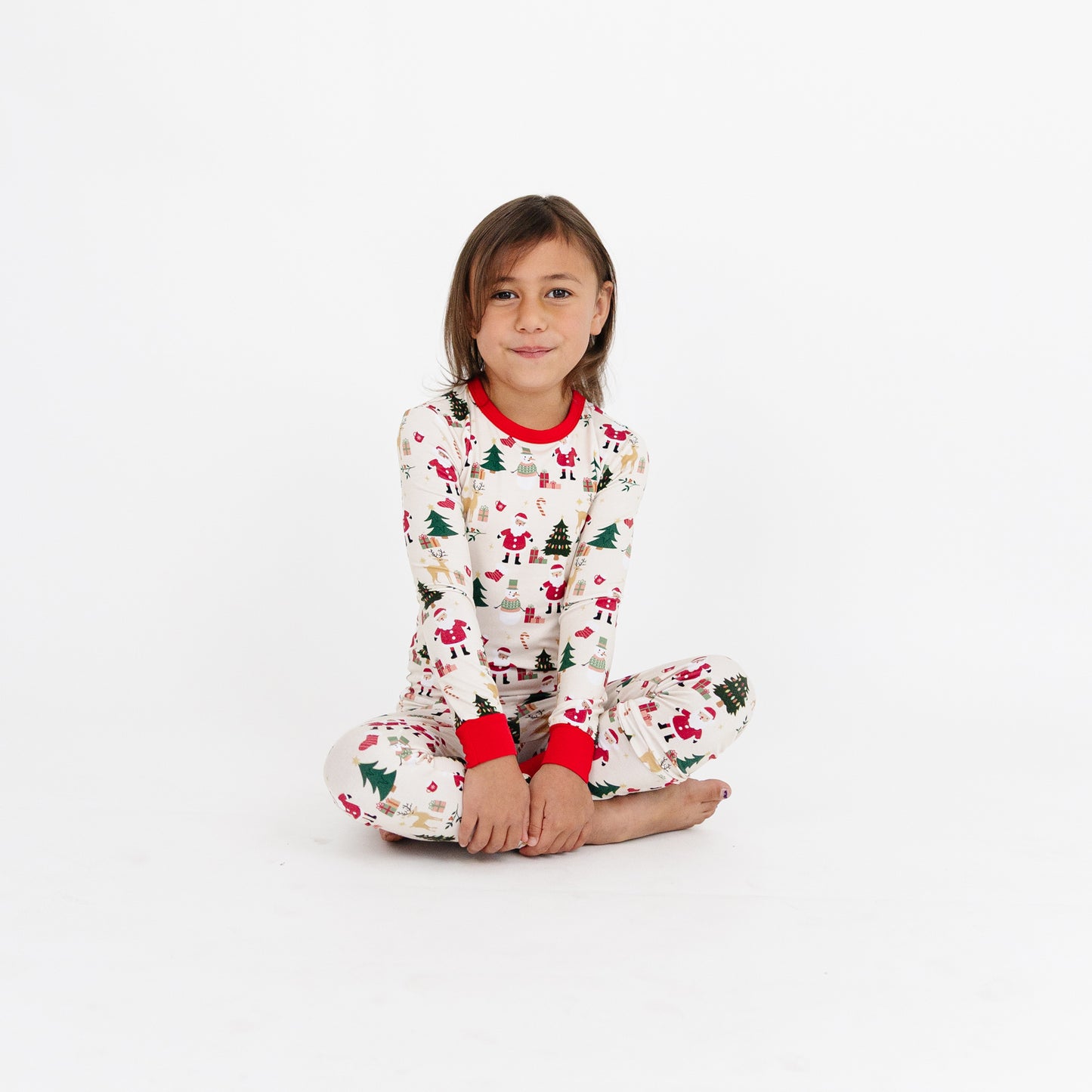 Girl sitting on the floor in Cozy Christmas bamboo pajamas, highlighting the soft, stretchy bamboo fabric and holiday print.