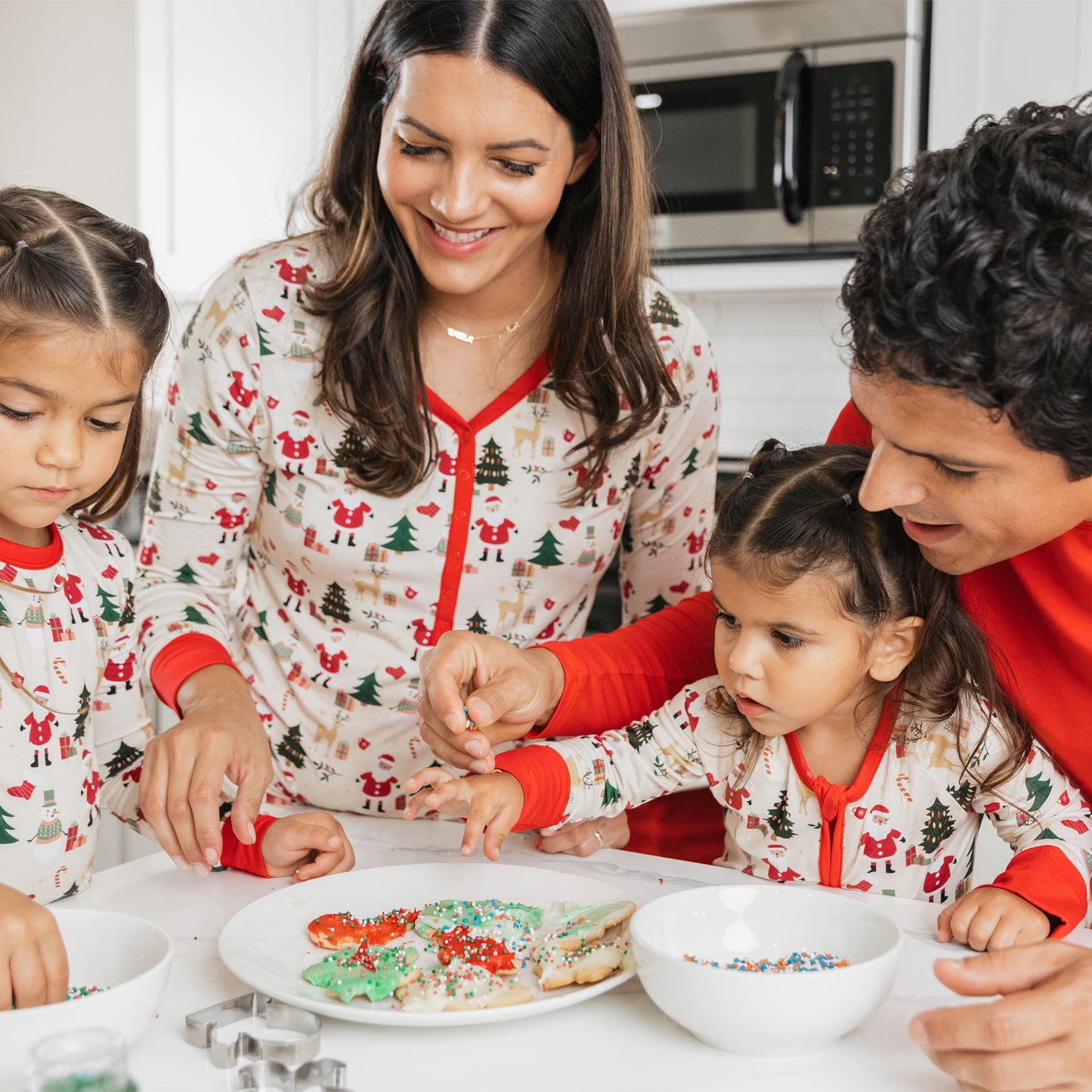 Mom and kids decorate cookies in matching Cozy Christmas bamboo pajamas, perfect for festive family traditions.