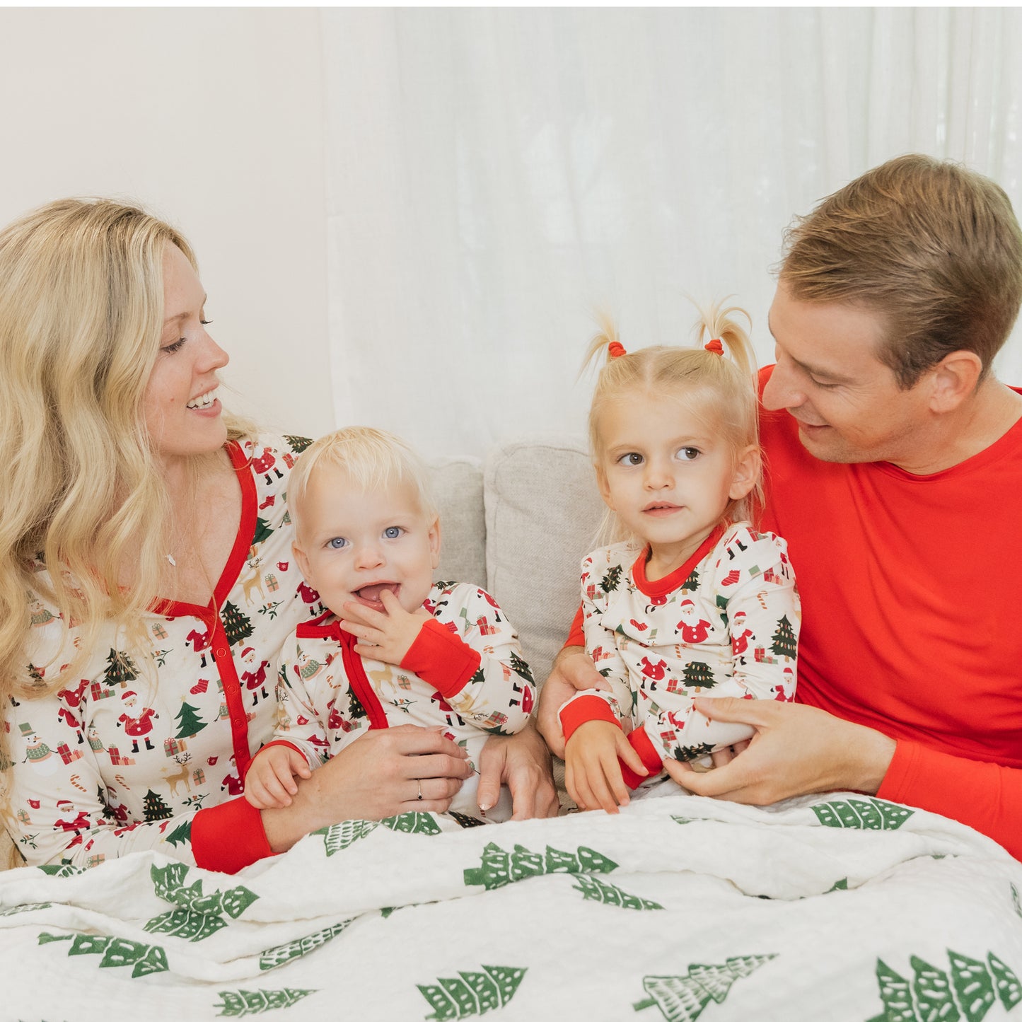 Family wearing Cozy Christmas bamboo pajamas enjoys cozy bedtime moments together in matching holiday prints.