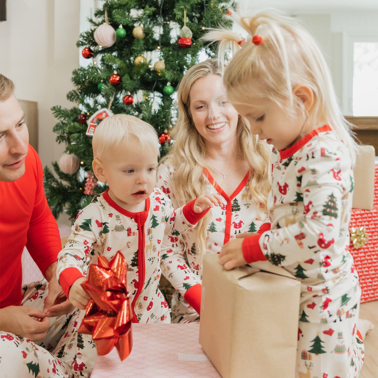 Family in Cozy Christmas bamboo pajamas gathers by the tree to open gifts, showcasing festive prints and cozy comfort.