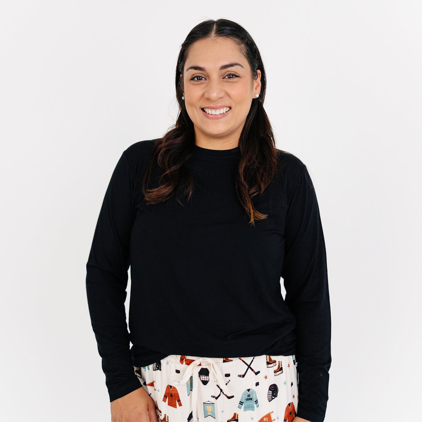 Woman wearing a black long-sleeve shirt and patterned pants on a white background