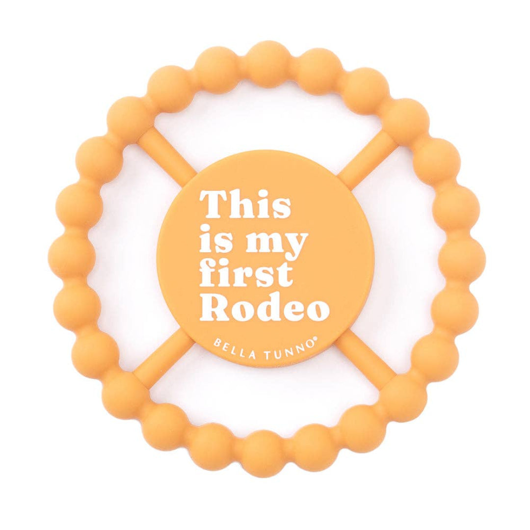 Round orange baby teether that says this is my first rodeo on the front