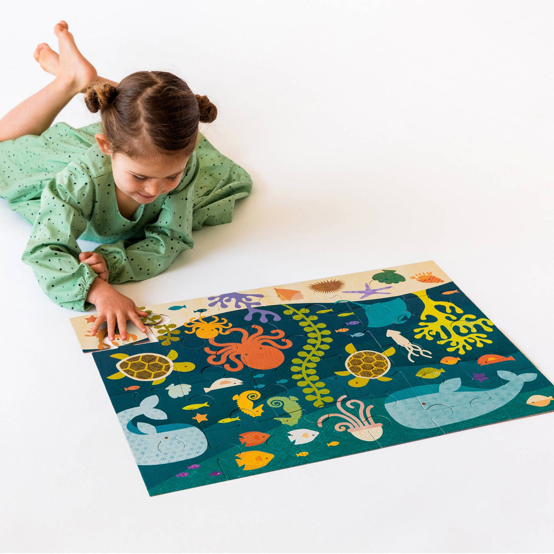 little girl doing a 24. piece ocean themed floor puzzle