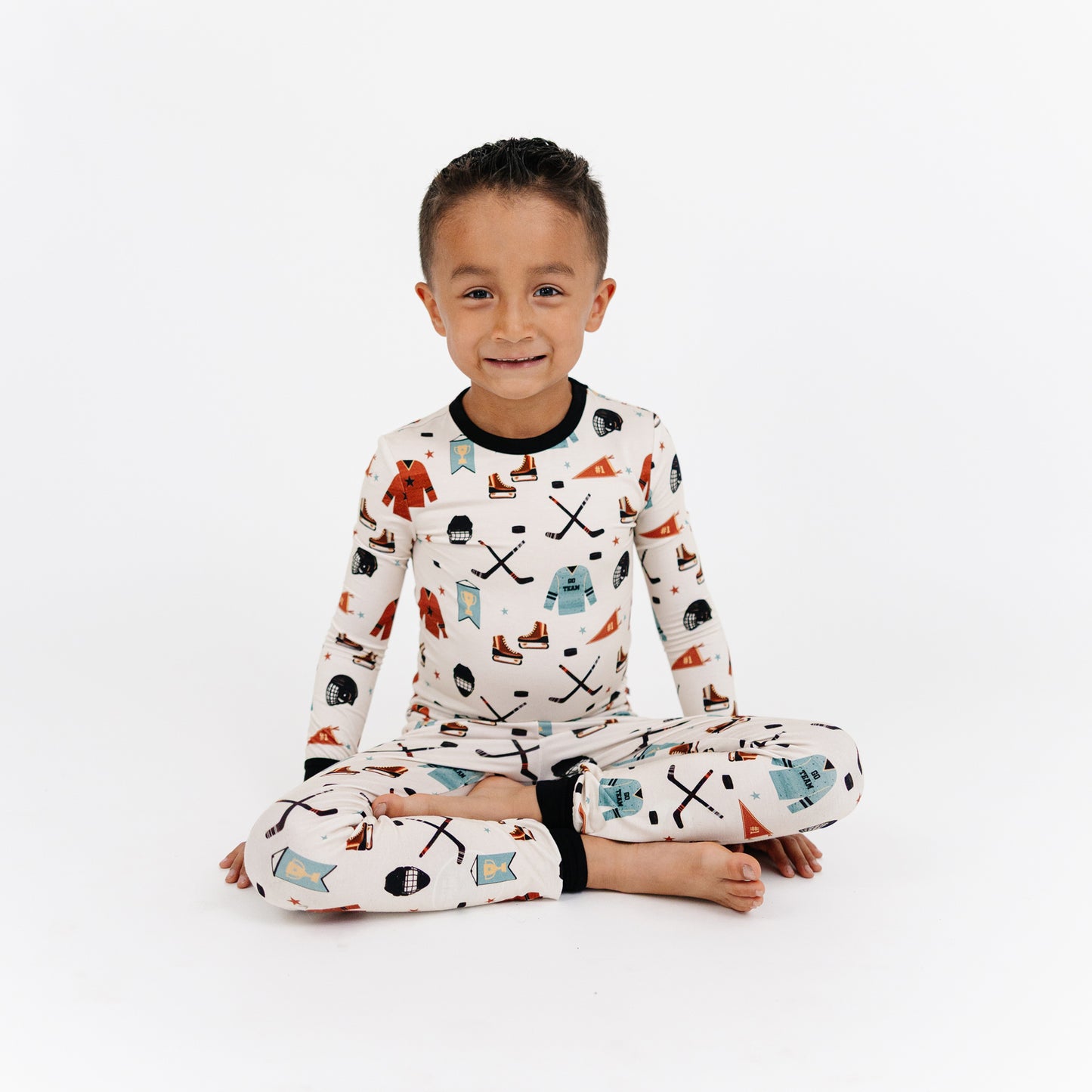 Child wearing pajamas with a pattern of skis, snowflakes, and other winter elements on a white background.