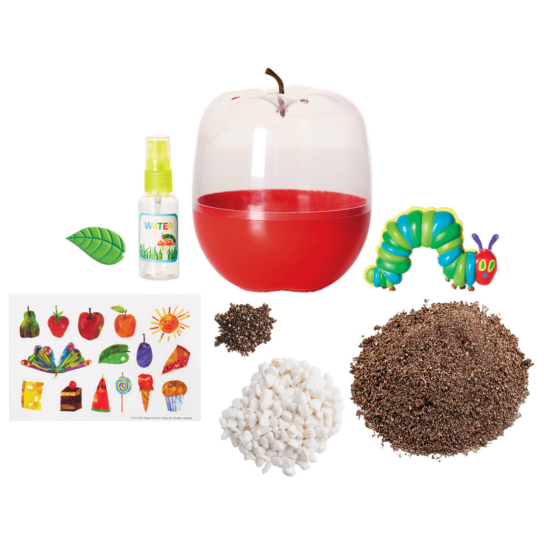 The Very Hungry Caterpillar grow kit contents including red apple-shaped terrarium, caterpillar figure, soil, white stones, chia seeds, spray bottle, decorative stickers, and leaf accent.