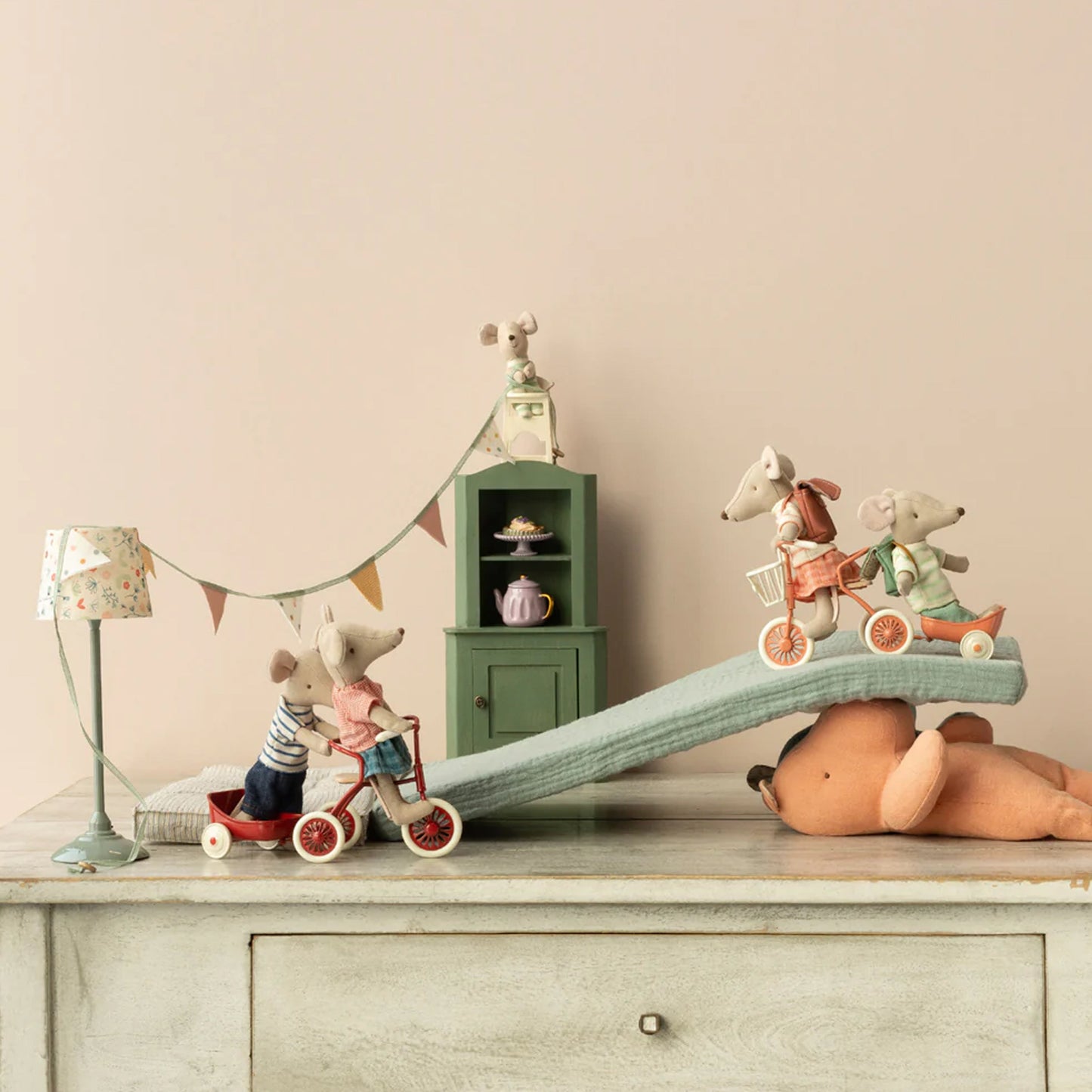 Children's toys on a dresser with a lamp and small cabinet in the background.
