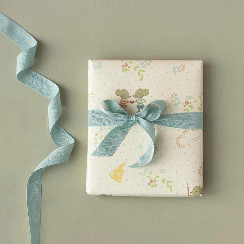Gift box with floral pattern and blue ribbon on a beige background
