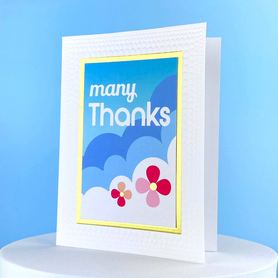 Greeting card that says many thanks and has clouds and flowers on it
