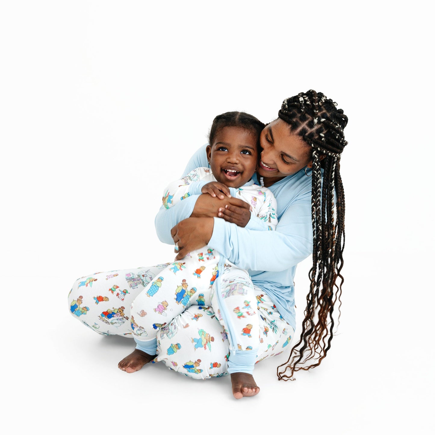 Mother and child hugging in matching pajamas on a white background