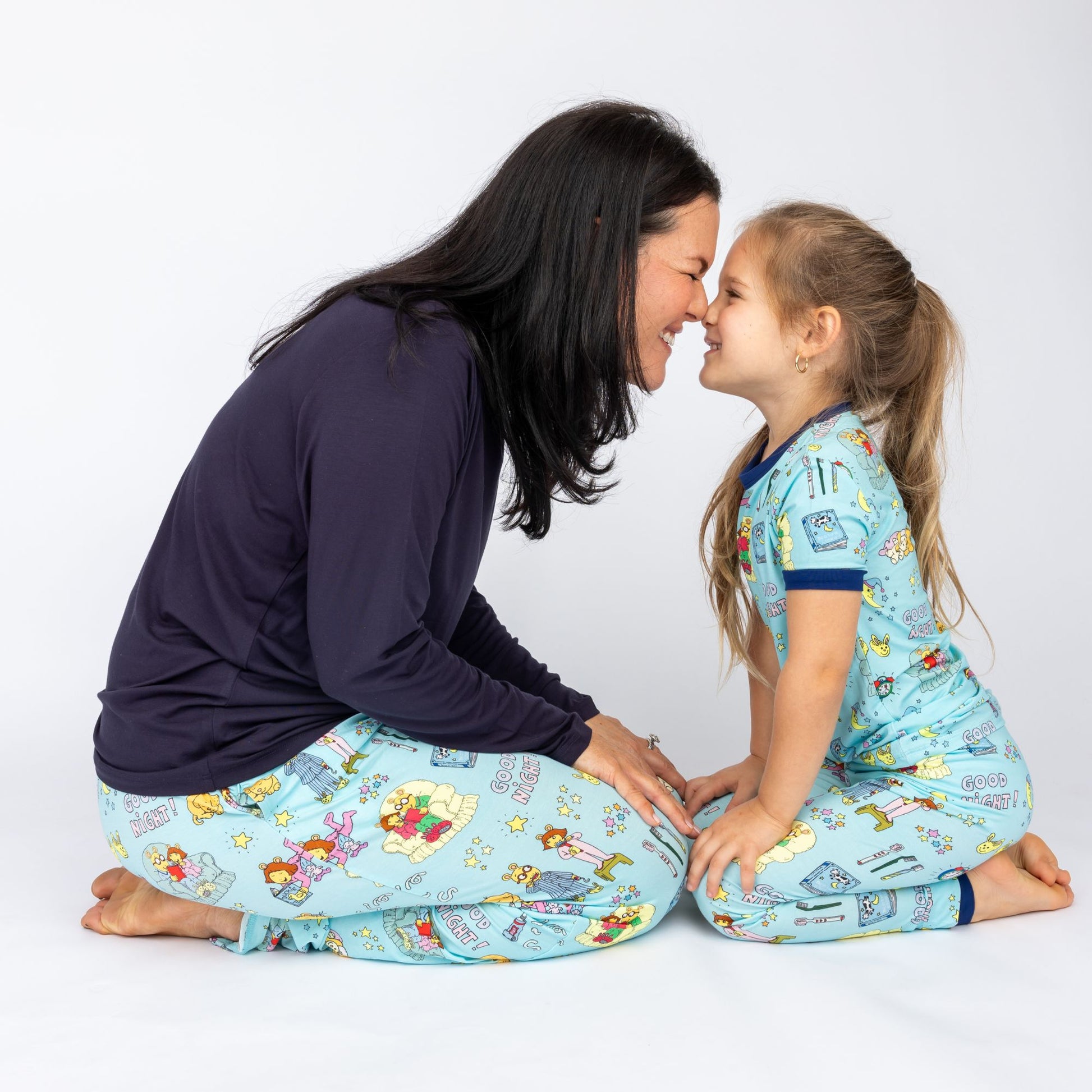Woman and child sitting on the floor wearing Good Night Arthur™ matching pajamas.