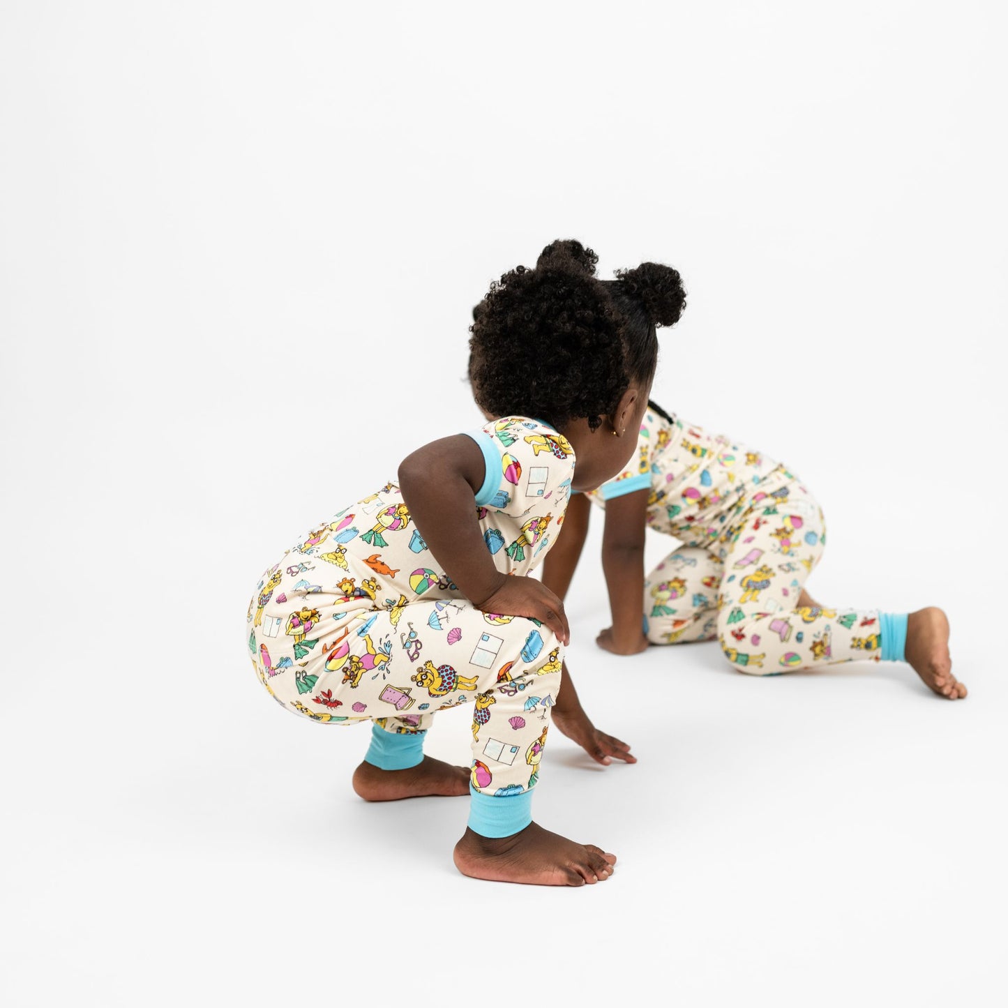 Matching siblings wearing our Arthur's Family Vacation Bamboo Short Sleeve Kids Pajama Pants Set featuring vibrant light blue trim and a playful print of Arthur™ in swimwear surrounded by fun beach props — perfect for family getaways.