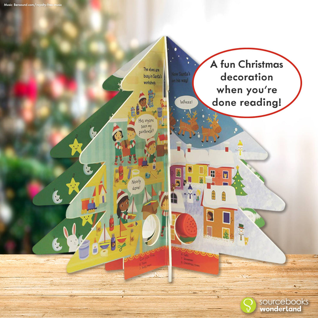a book shaped like a christmas tree on a table in front of a real christmas tree